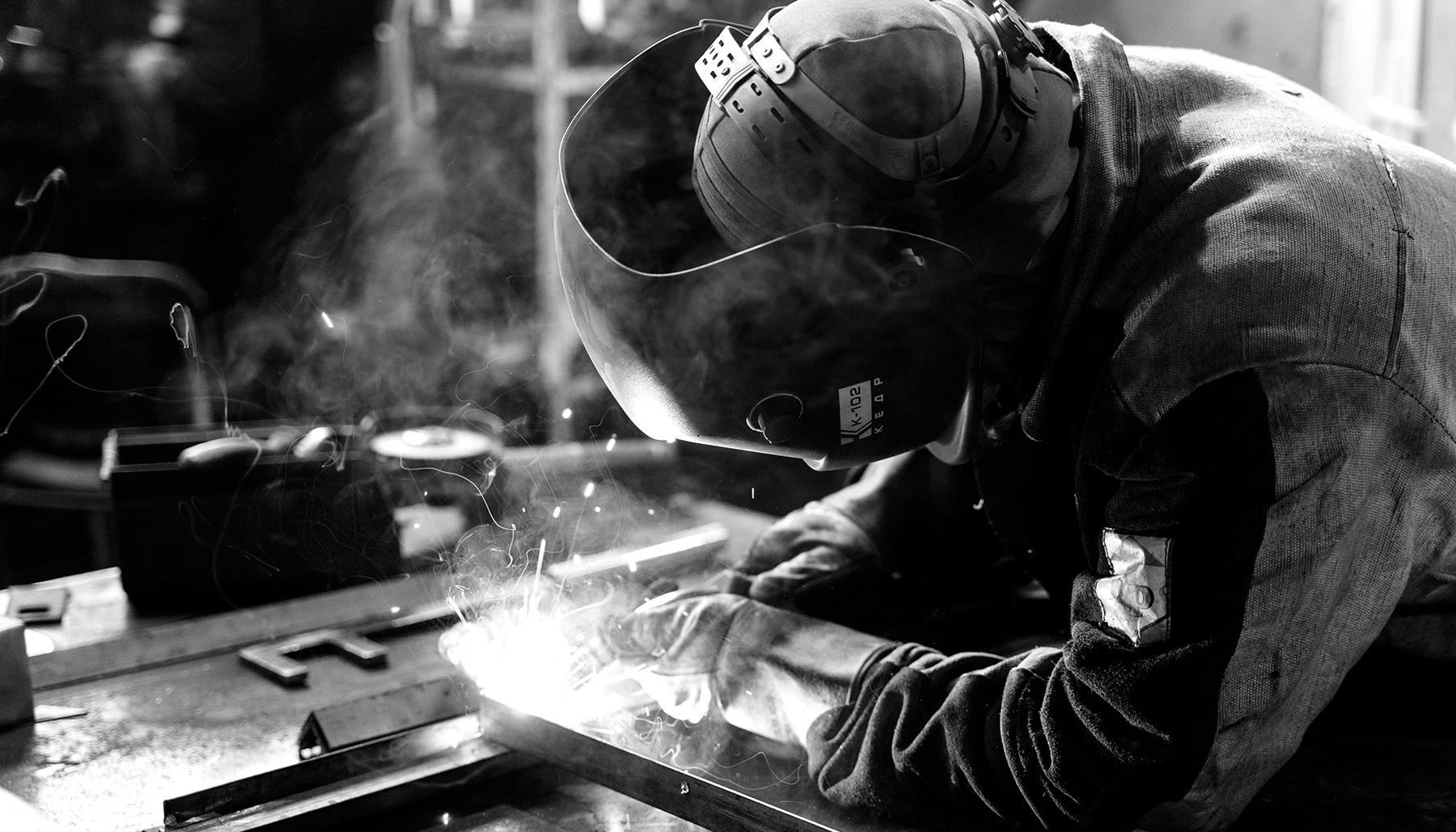 Imagen de un soldader soldando metal en blanco y negro